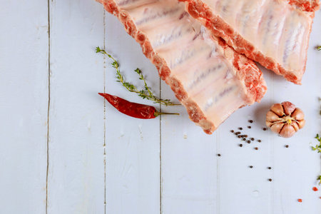 Raw fesh beef spare ribs with herbs on white background.