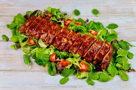 Baked juicy barbecue beef ribs with BBQ sauce and salad on wooden table.の写真素材