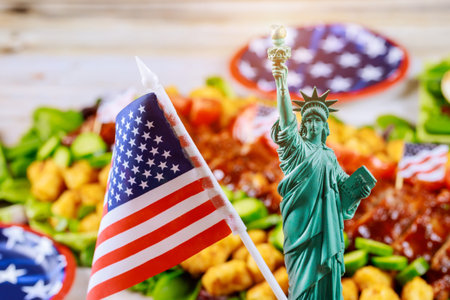 Statue of Liberty and american flag on party table with blurry food not in focuse. Independence Day.