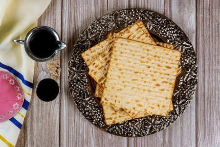 Matza, wine, tallit and kippa on wooden background. Jewish holiday concept.