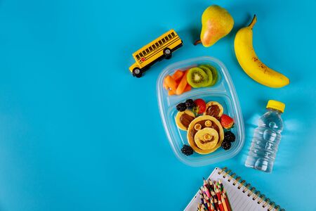 Lunch container with pancakes, carrot, pear and banana with scool supplies. Back to school concept. Top view, copy space.の写真素材