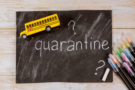 Quarantine in school for student concept. Chalkboard, color pencils and bus toy.