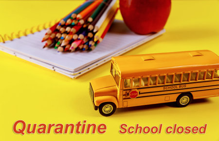 School bus toy and notebook with color pencils. Quarantine concept.