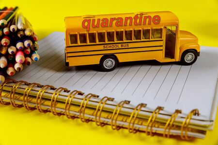 Student quarantine in school concept. Notebook, color pencils and bus toy.の写真素材