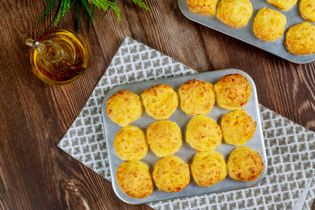 Baked brazilian cheese bread in baking pan with oil on wooden table.