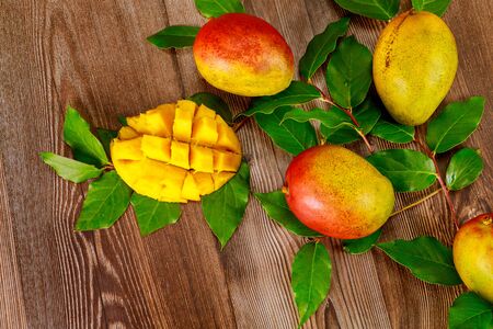 Ripe mango with green leaves on wooden background.の写真素材