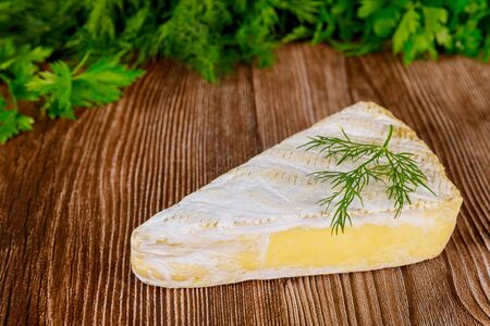 Slice of brie creme cheese with parsley on wooden background.の写真素材