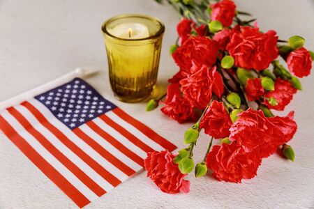 American flag and candle with red flowers carnation on white surface. Veterans Day.の写真素材