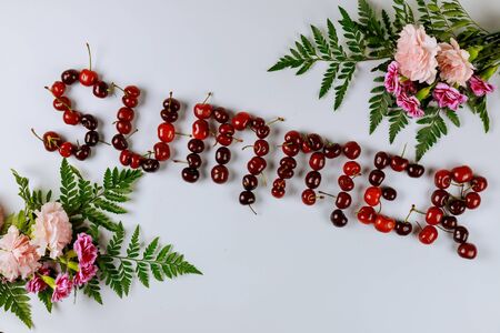 Word summer made from cherries and flowers on white background. Top view.の写真素材