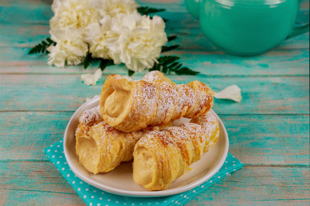 Puff pastry cones filled with caramel cream on wooden background. Close up.