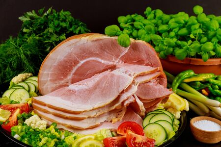 Whole baked honey sliced ham with vegetables and green herbs.の写真素材