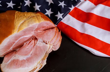 Sliced smoked whole ham in bone with american flag.の写真素材