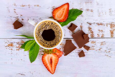 Natural dark coffee with strawberry and chocolate on white wooden table. Top view.の写真素材