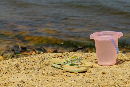 Abstract background of travel. Bucket and flip flops on shore. Soft focus.の写真素材