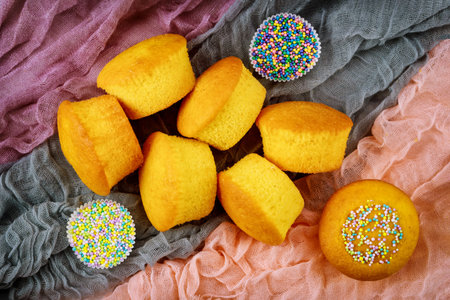 Vanilla peeled cupcakes from parchment paper with sprinkles. Top view.