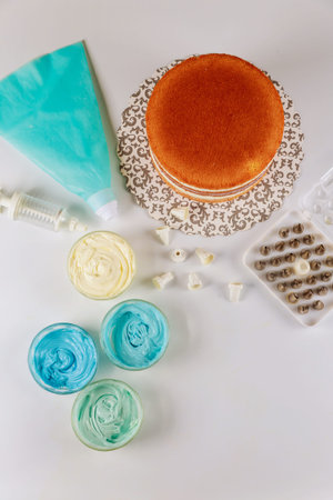 Sponge layered cake with icing and tools for decoration.