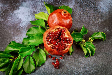 Fresh ripe pomegranate with green leaves on dark background. Close up.の写真素材