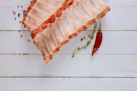 Fresh raw pork ribs with marinade ingredients on old white wood backgroundの写真素材
