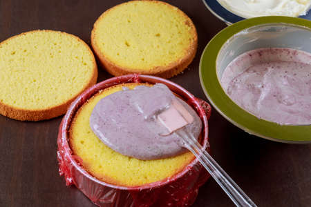 Making festive cake with purple fruit cream and white cream.の写真素材