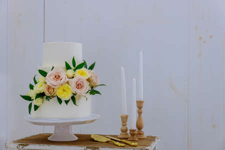 White wedding cake with fresh flowers and candles on white background.の写真素材