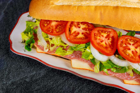 Sub made from french bread, muenster cheese, salami and vegetable. Take out food or fast food concept.の写真素材