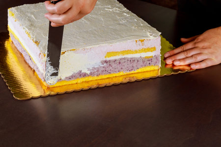 Chef cover with white icing festive cake. Making layer sponge cake.