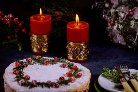 Festive holiday pie with cranbarry decoration on black table with burning candles and pine branches. Christmas night.の写真素材