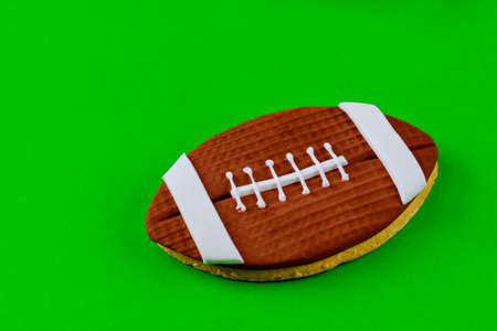 Rugby ball cookie on green background. American football background.の写真素材