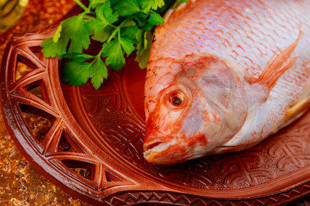 Pink tilapia fish with herbs and lemon on tray. Close up.の写真素材