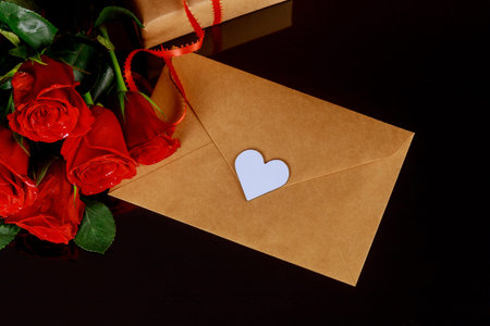 Red roses with greeting card on black table. Valentines day concept.