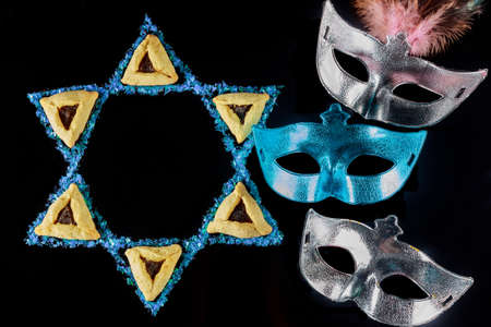 Star of David with mask and cookies. Jewish symbol on black background.の写真素材