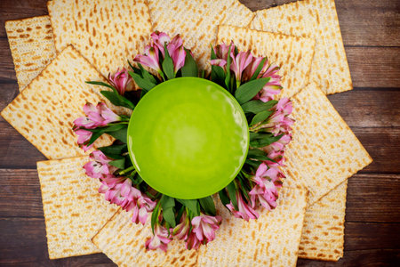 Composition with matzo bread, plate and pink flowers. Top view. Passover Jewish holiday.