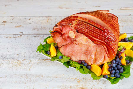Spiral sliced hickory smoked ham with fresh orange and blueberries. Holiday meal.の写真素材
