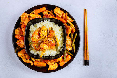 Asian stir fry meat, vegetables with white rice and chopstick.の写真素材