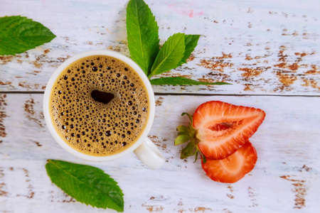 Natural dark coffee with strawberry on white wooden table. Top view.の写真素材