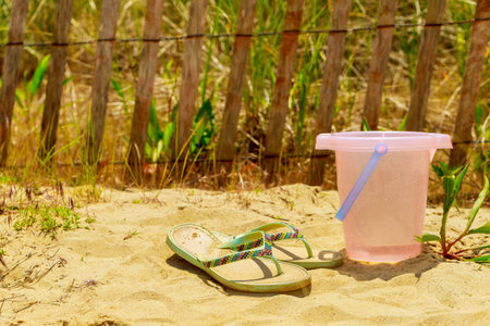 Abstract background of travel. Bucket and flip flops on shore. Soft focus.