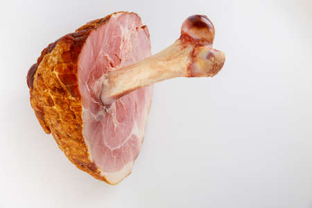 Glazed pork ham with big bone on white isolated background. Close up.の写真素材