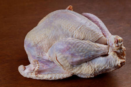 Fresh raw whole turkey on wooden background. Thanksgiving dish.の写真素材