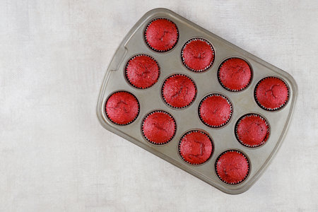 Twelve red velvet cupcakes in baking pan on white background. Top view.の写真素材