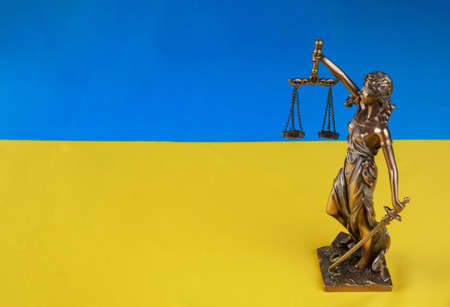 Lady Justice holding the scales on flag of Ukraine background. Russian terrorist attack.の写真素材