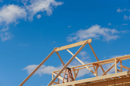 Wooden roof truss framing under construction in new home with a clear sky viewの写真素材
