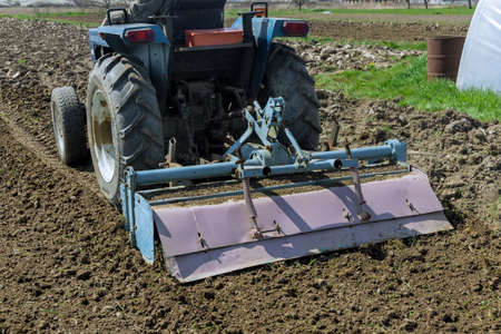 Tractor loosens and cultivates soil on field. Prepare for seedling.の写真素材