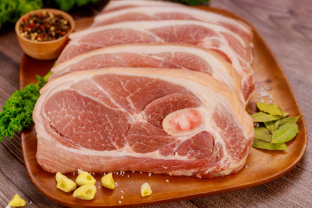 Pork shoulder cut into slices and spiced on wooden board.の写真素材
