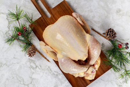 Prepared raw whole chicken for Christmas dinner on wooden board.の写真素材