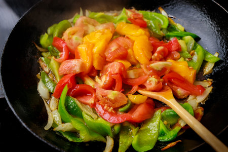 Stir-fried tomatoes and bell peppers in an iron pan.の写真素材