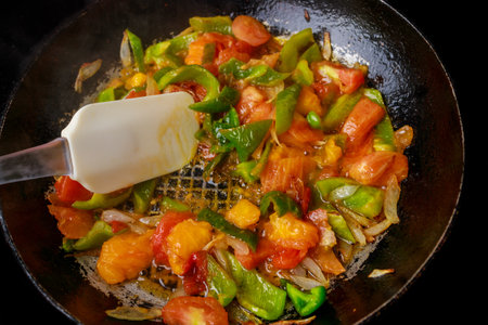 Using iron pan, stir-fry tomatoes and bell peppers.の写真素材