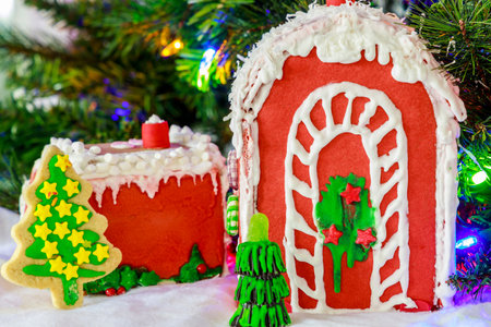 Colorful gingerbread houses and festive cookies arranged together, showcasing intricate designs of icing and candy decorations. They set against backdrop of holiday lights.の写真素材