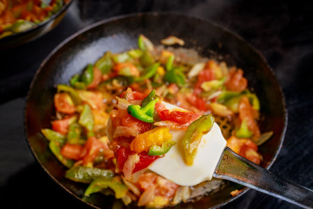 Fresh tomatoes and various bell peppers being saut ed together in skillet, creating vibrant and flavorful vegetable dish. Mixture colorful and aromatic.の写真素材