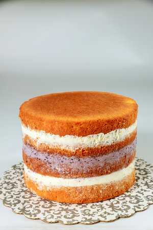 Delightful layered sponge cake showcases three distinct colors of filling between fluffy layers, perfect for special occasions. Cake elegantly presented on decorative stand.の写真素材