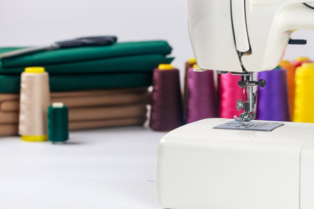 Sewing machine positioned prominently in well-lit crafting area, surrounded by colorful thread spools and neatly arranged fabric, showcasing artistry of sewing.の写真素材
